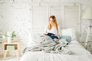 Cute Redhead Woman Reading Book at Home. Girl with Grey Woolen Blanket