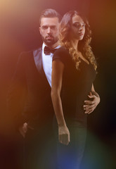 embraced elegant couple holding hands and look at the camera