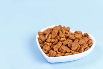 Dry cat food in the form of hearts lies in the saucer in the form of heart