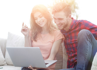 young man with his girlfriend watching a TV show on the laptop sitting in the living room