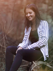 Obraz premium young woman sitting on a log in the woods.