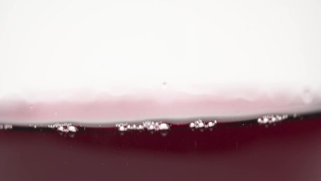 Glass of Red zinfandel wine slowly swilring in glass on stark white background. Passion style footage of Easter scenes