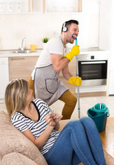 Man mopping floor and singing to girl on sofa