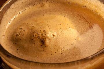 Cappuccino coffee in a glass. Texture of orange foam.