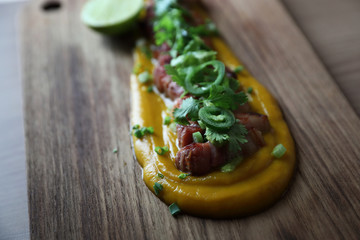 Grilled bacon with pumpkin sauce on wood background