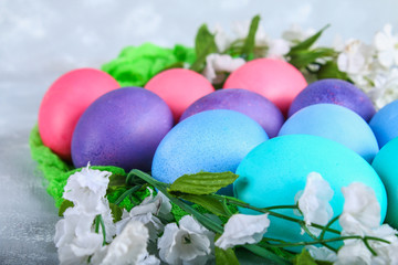 Colored Easter eggs with white flowers on a gray concrete background.