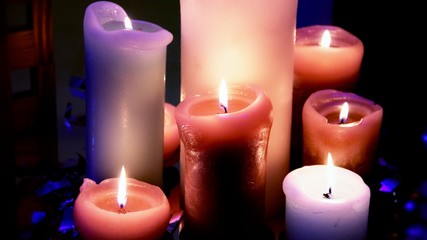 Group of burning candles on table with glowing surface 
