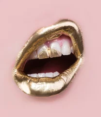 Foto op Plexiglas Fashion lips Gouden lip make-up. Gouden verf op lippen en tanden. Open mond en witte tanden geïsoleerd op roze achtergrond. Een deel van rijk gezicht bedekt met goud. Moderne make-up voor vrouwen. Sensueel gouden luxe concept