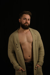 young model posing in the studio, wearing a cardigan and hands in pockets and bearded.