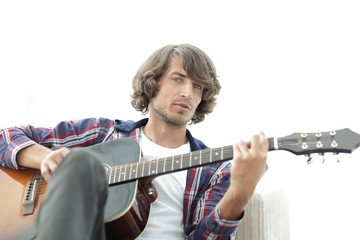 Handsome man playing on the guitar on the couch at home