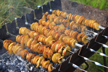 Potato skewers with bacon. Marinated shashlik preparing on barbecue grill over charcoal