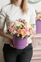Selective focus on bouquet in lilac hatbox. beautiful luxury bunch of mixed flowers in womans hand. the work of the florist at a flower shop. perfect gift or compliment.