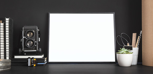 Mock up photo frame with camera. White blank frame and medium format camera on photographer table.