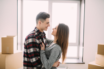 Young couple hug and kiss while moving to a new apartment together relocation