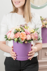 Selective focus on bouquet in lilac hatbox. beautiful luxury bunch of mixed flowers in womans hand. the work of the florist at a flower shop. perfect gift or compliment.