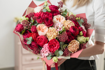 bouquet of highly red coloured . beautiful luxury bunch of mixed flowers in womans hand. the work of the florist at a flower shop.