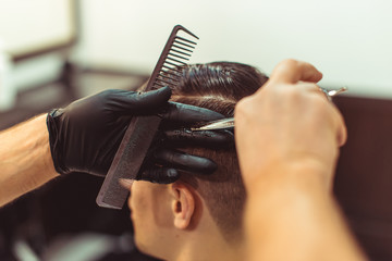 Barber using scissors and comb. Man haircut in the barbershop.