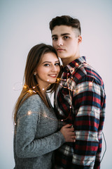 Young couple in love hug each other with lights on the white background