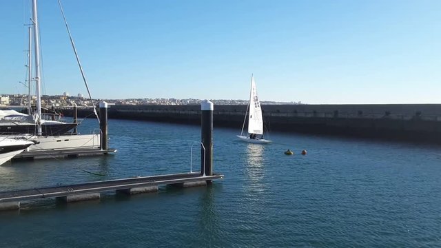 Sail boat maneuvering in big  portugal yacht marina filmed from mega yacht