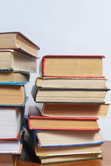 Stack of different books on a table against a white wall background