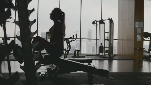 Sportswoman doing situps in gym. Muscular female athlete doing abs workout. Silhouette of slim athletic girl. Active and healthy lifestile concept.