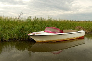 Widok na motorówkę zacumowaną w wysokiej trawie   © summit fever