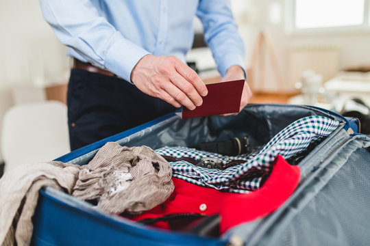 Man preparing for business travelling. Open traveler's bag with passport, clothing and accessories. Travel and vacations concept.