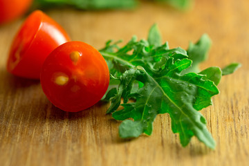 Cherry tomatoes and baby kale in macro on wooden cutting board
