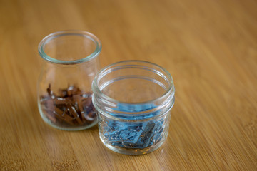 Tiny colorful pins in glass jars in macro with wooden background