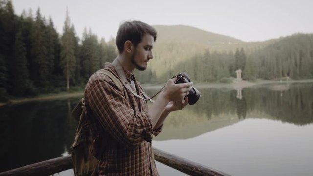 A man is a tourist on a lake in the mountains, taking pictures. Recreation. Travel. Nature. Photographer