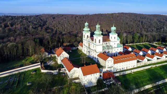 Camaldolese monastery and baroque church in the wood on the hill in Bielany, Krakow, Poland , Aerial 4K video in sunset light in winter with Vistula River and far view of Cracow city in the background