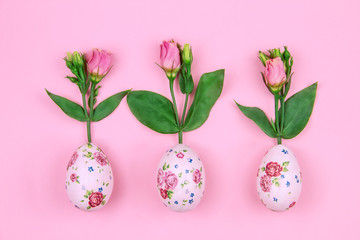 Happy Easter and Spring is coming concept. Fresh spring's red flowers roses grow from easter eggs with flower pattern on pink background.