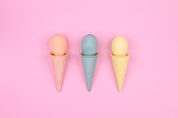 Happy Easter Day. Pink, blue and yellow tradition easter eggs with waffle cone on pink background