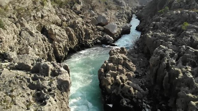 survol au ralenti d'une rivi&egrave;re et ses rapides bleus verts dans un canyon 