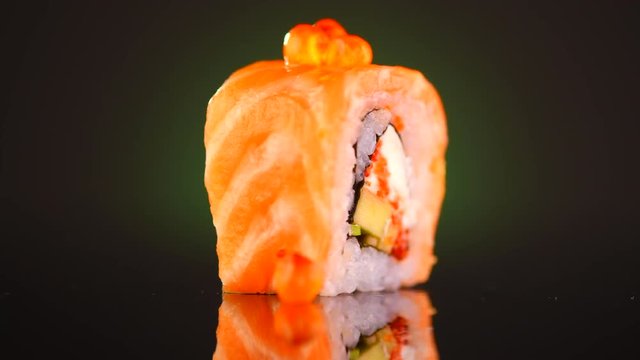Sushi roll with tuna, vegetables, flying fish roe and caviar closeup. Japanese food. Sushi roll rotated over black background. 4K UHD video footage. 3840X2160