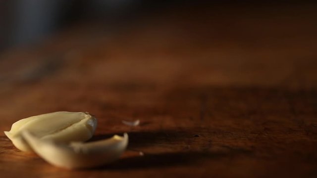 Knife crushes unpeeled garlic cloves, close up