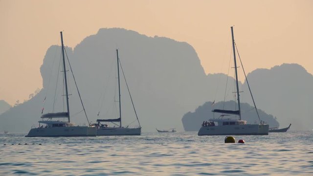Group of yachts catamarans sailing in the Andaman sea with Koh Poda island on the background