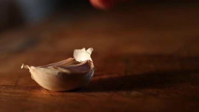 Unpeeled garlic clove crushed by knife, close up