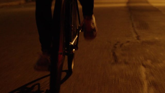 Closeup of feet pedaling bike at night