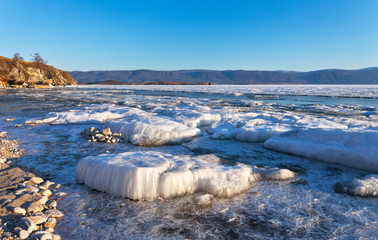 Baikal Lake. Coast of Olkhon Island in spring morning. Large ice floes are melting on the shore