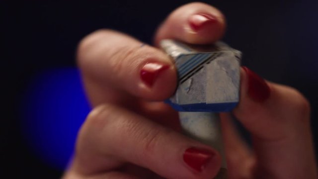 Closeup of woman's hand rubbing chalk on the end of a pool stick