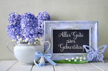 Blue decorations and hyacinth flowers on white table, blackboard with text 
