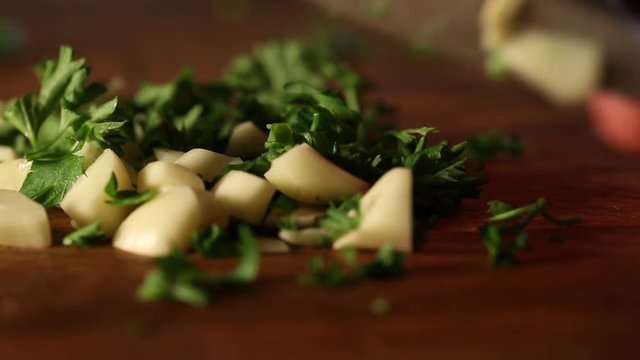 Close up, knife chops parsley and garlic