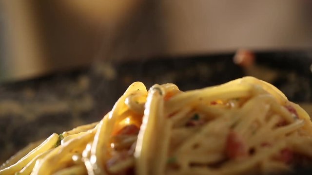 Close up, tongs pick up pasta noodles close up