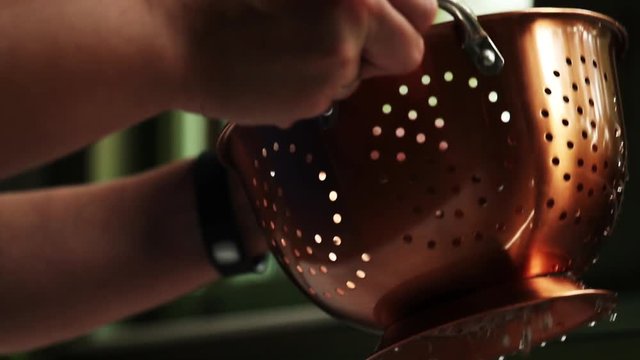 Person washes cooking strainer, slow motion