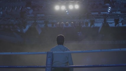 Back view of working gaffer or lighting technician and spotlights background. Lighting technician, placing the light during a film. Lighting technicians operating strobes during a concert