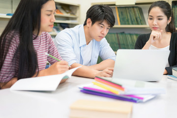 Group of Happy young people using labtop computer working homework together in Library. Students is Brainstorming for homework. Setup studio shooting.