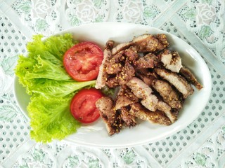 Grilled pork marinate with Thai herbs, Thai style spicy grill pork serve with lettuce and tomato slices 