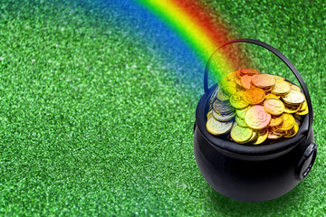 Saint Patrick's Day and Leprechaun's pot of gold coins concept with a rainbow indicating where the...