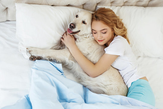Beautiful teen girl with golden retriever dog in a bed